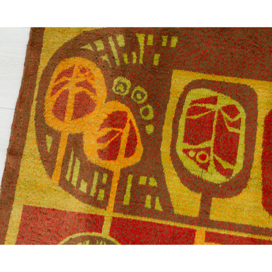 A close-up of the mid-century tapestry design featuring stylized trees and geometric motifs in rust red, mustard yellow, burnt orange and brown.