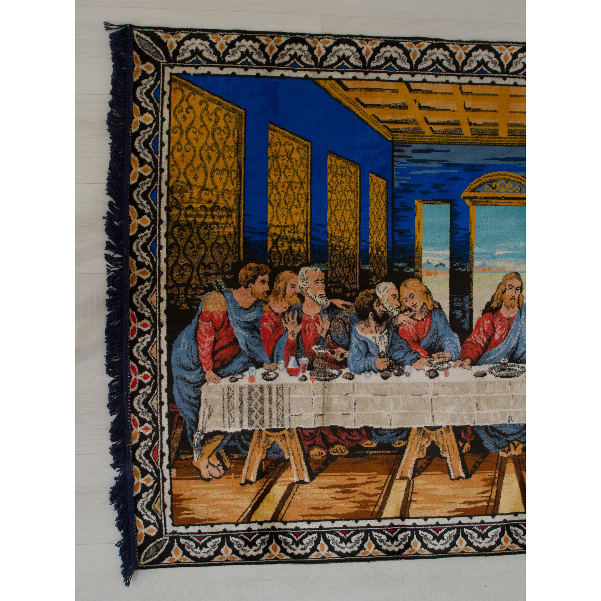 Closer look at the left half of the vintage tapestry, showing the apostles reacting around the long dining table against a rich cobalt blue background.