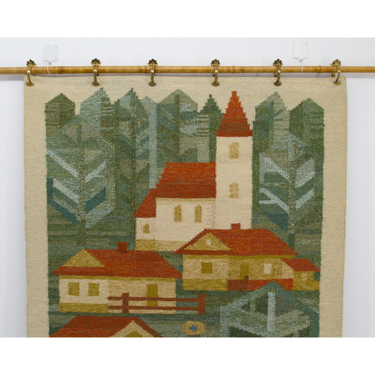 A detailed view of the top half of the geometric handwoven textile, highlighting the beautifully woven rural church, tall green trees, and rich wool colors.