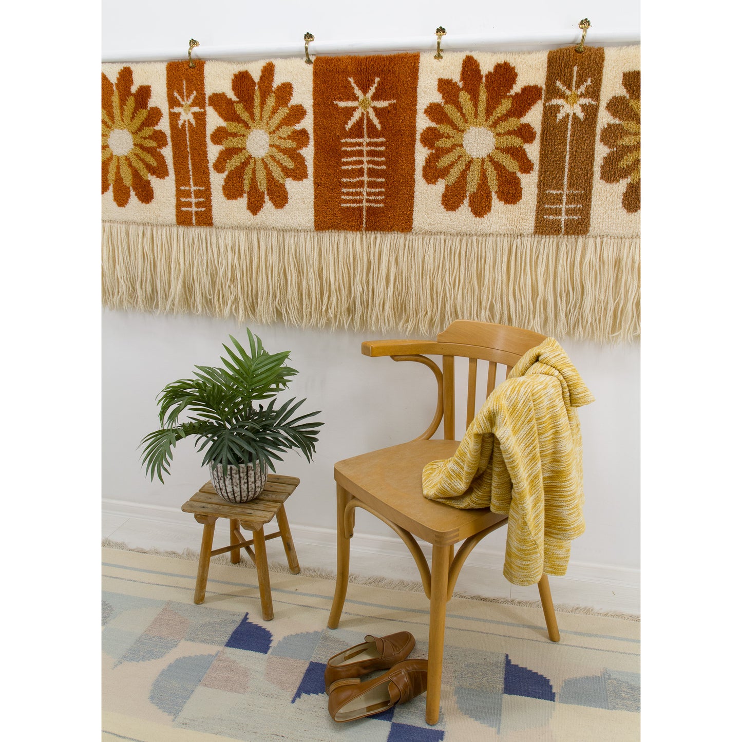 The wide floral tapestry displayed above a bentwood dining chair. The tapestry adds a warm, romantic 70s retro vibe to the room.