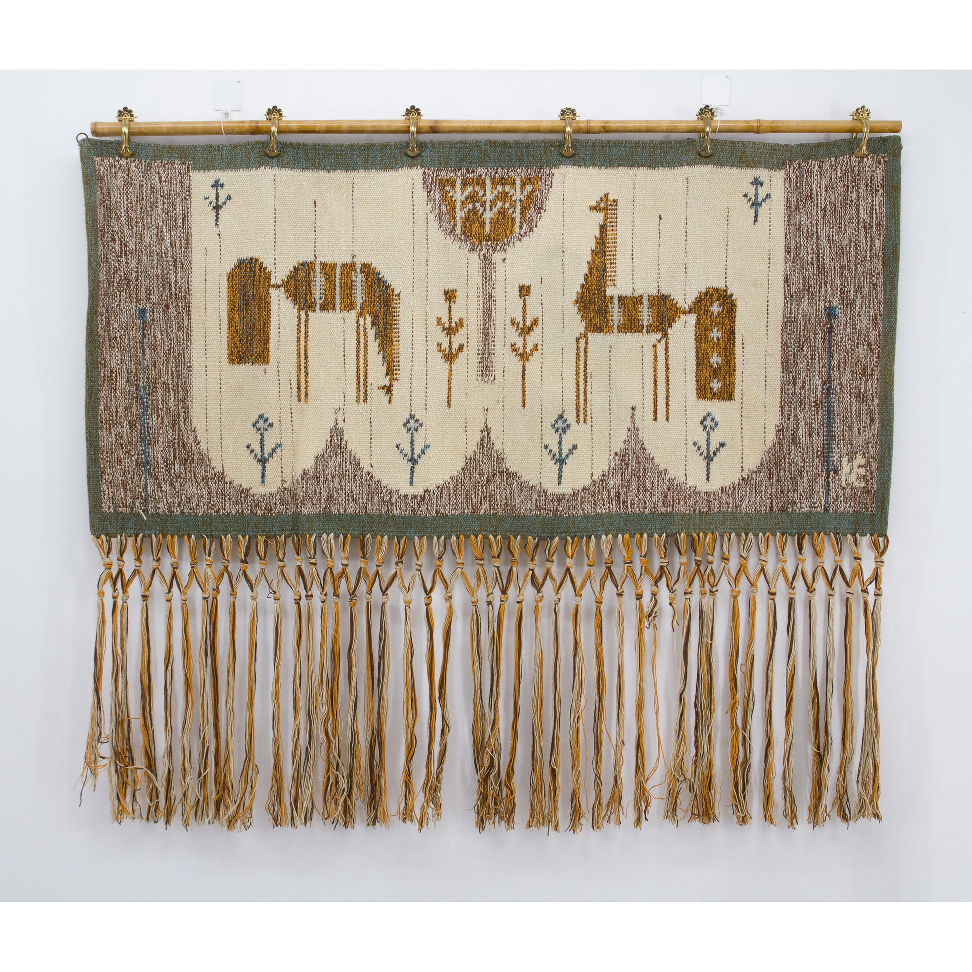 Full straight-on view of the earthy mid-century bohemian tapestry hung beautifully on a bamboo rod, featuring stylized geometric horses in brown and mustard.