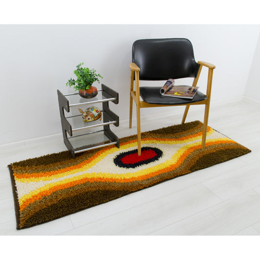 A textured rya rug serving as a strong, bold design accent in a room setting, styled with a modern black lounge chair. The vintage shag rug is creating a vibrant focal point for mid-century living room interior design.