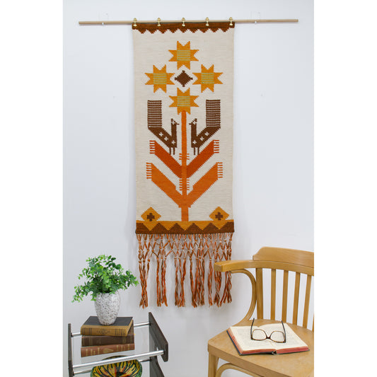 Full vertical view of the Eva Nemeth tapestry hanging on a white wall above mid-century furniture. Demonstrates the dramatic length and the visual impact of the extra-long fringe.