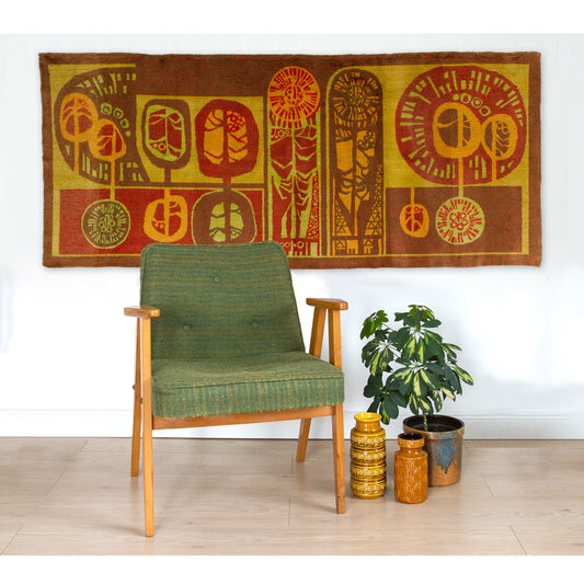 Vintage 60s home decor wall tapestry styled majestically behind a green mid-century armchair, showcasing its massive scale and warm golden brown palette.