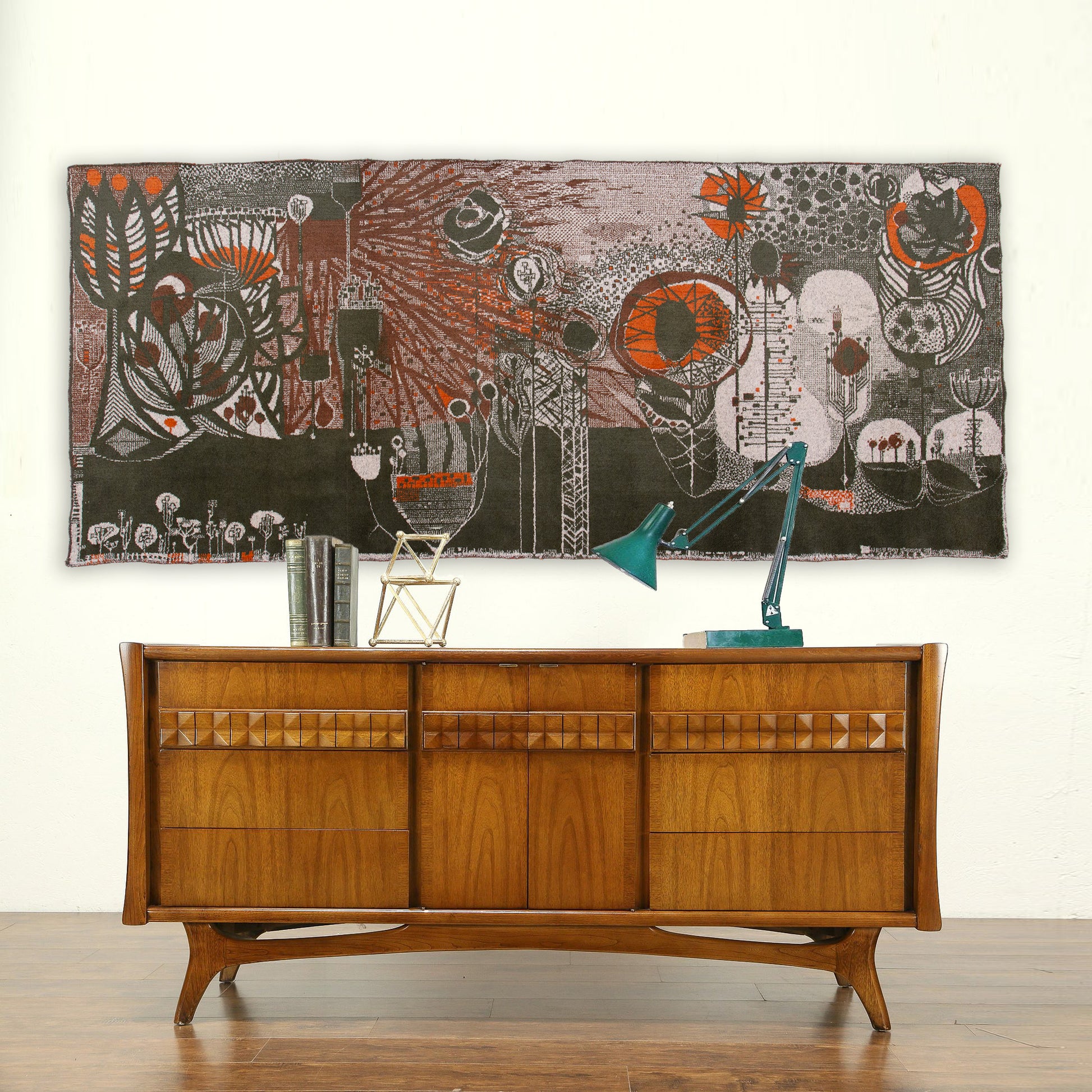 Large vintage 1960s tapestry by László Pécsi styled above a wooden mid-century credenza. The abstract brutalist wall art features a striking, dark moody color palette with vivid orange and white organic shapes.