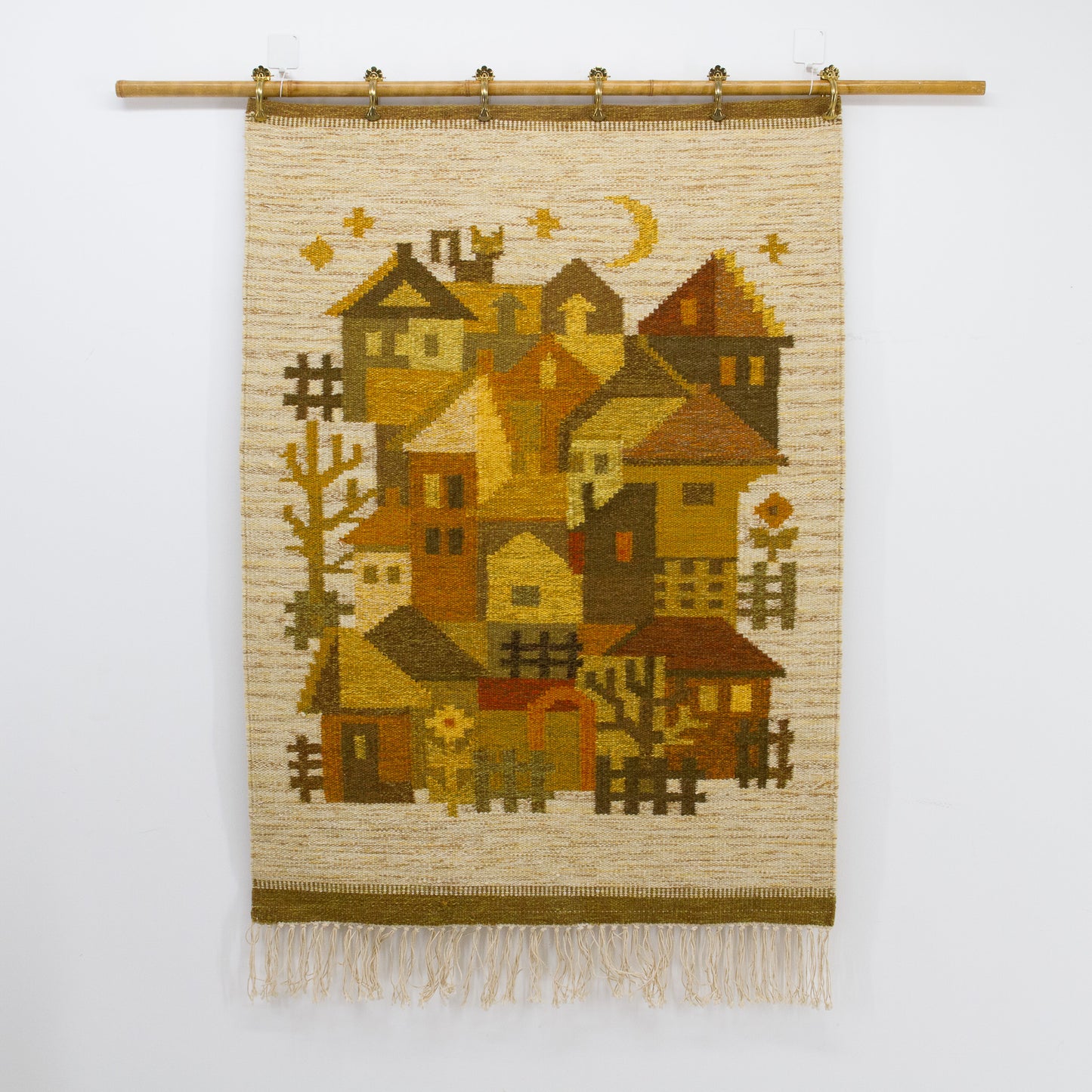 Straight on, un-obstructed flat lay view of the handwoven folk art tapestry showing a rustic stylized townscape under an amber yellow moon.
