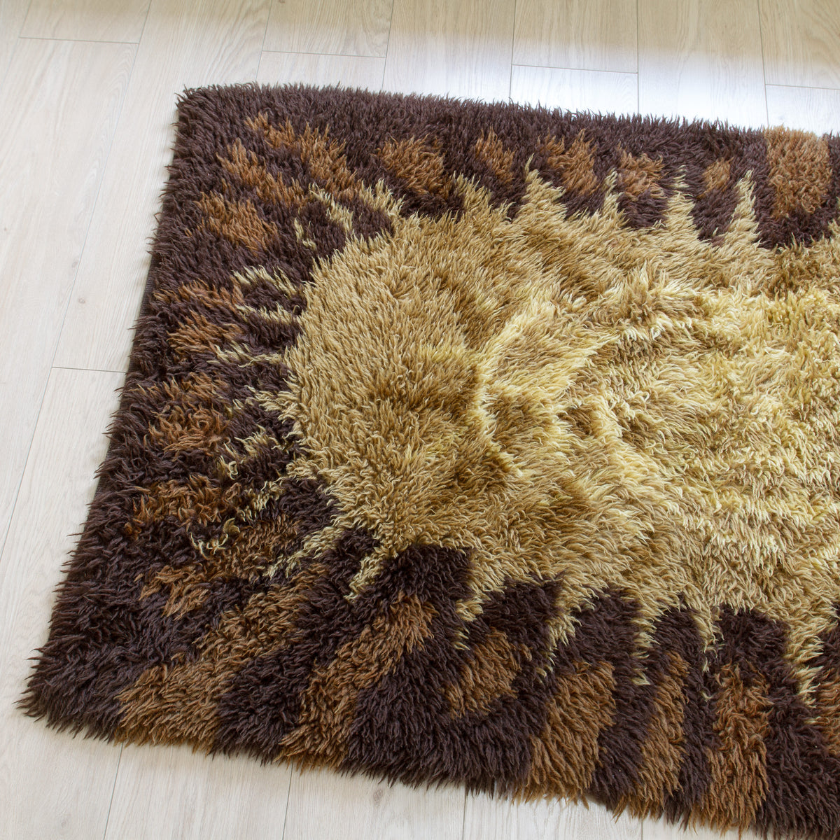 Vintage shag accent rug with a sunburst pattern in shades of brown, tan, and beige, perfect for a cozy nordic or japandi style interior.