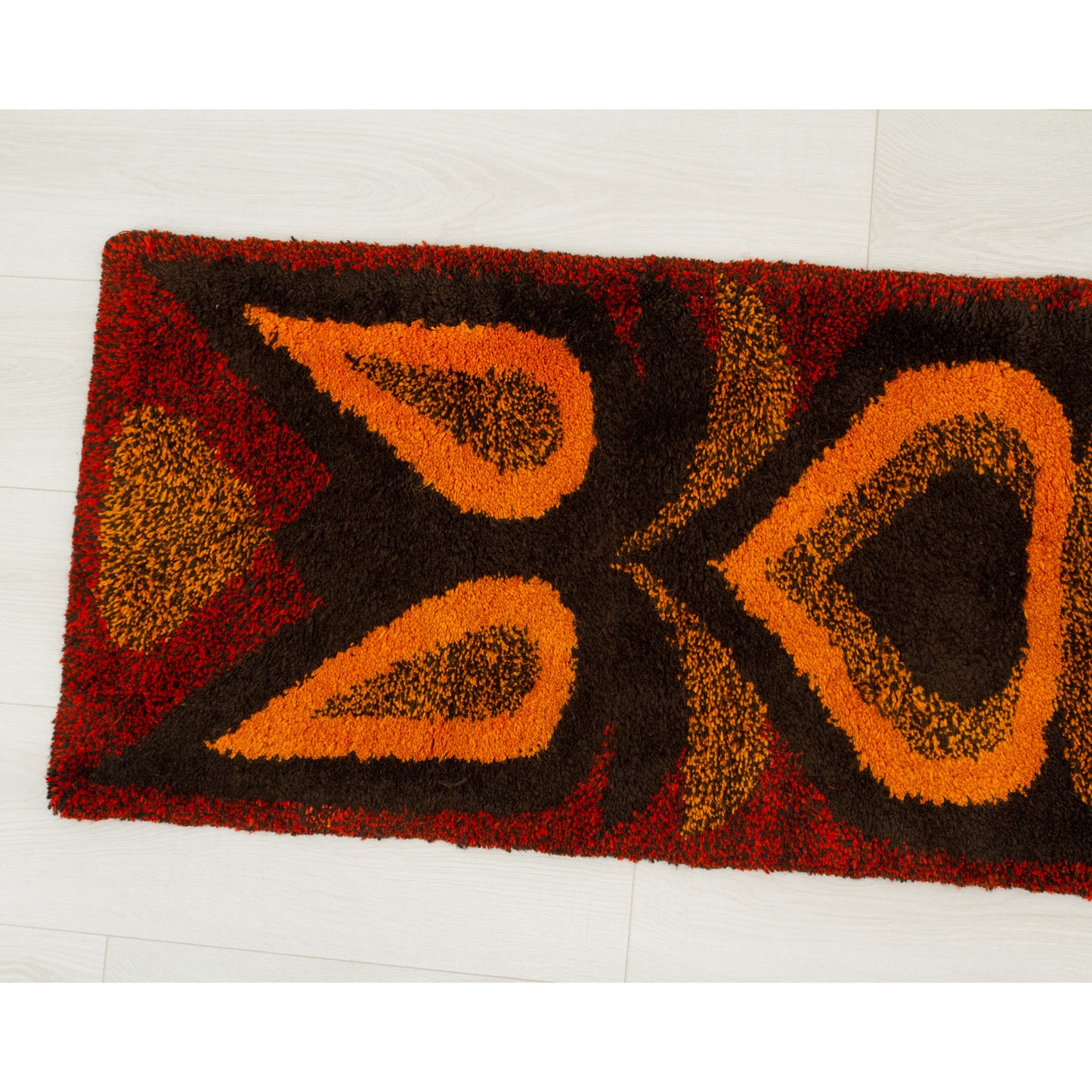 Top view of the left segment highlighting the densely tufted mid-century pattern of sweeping diamond and oval motifs in vivid autumn retro colors.