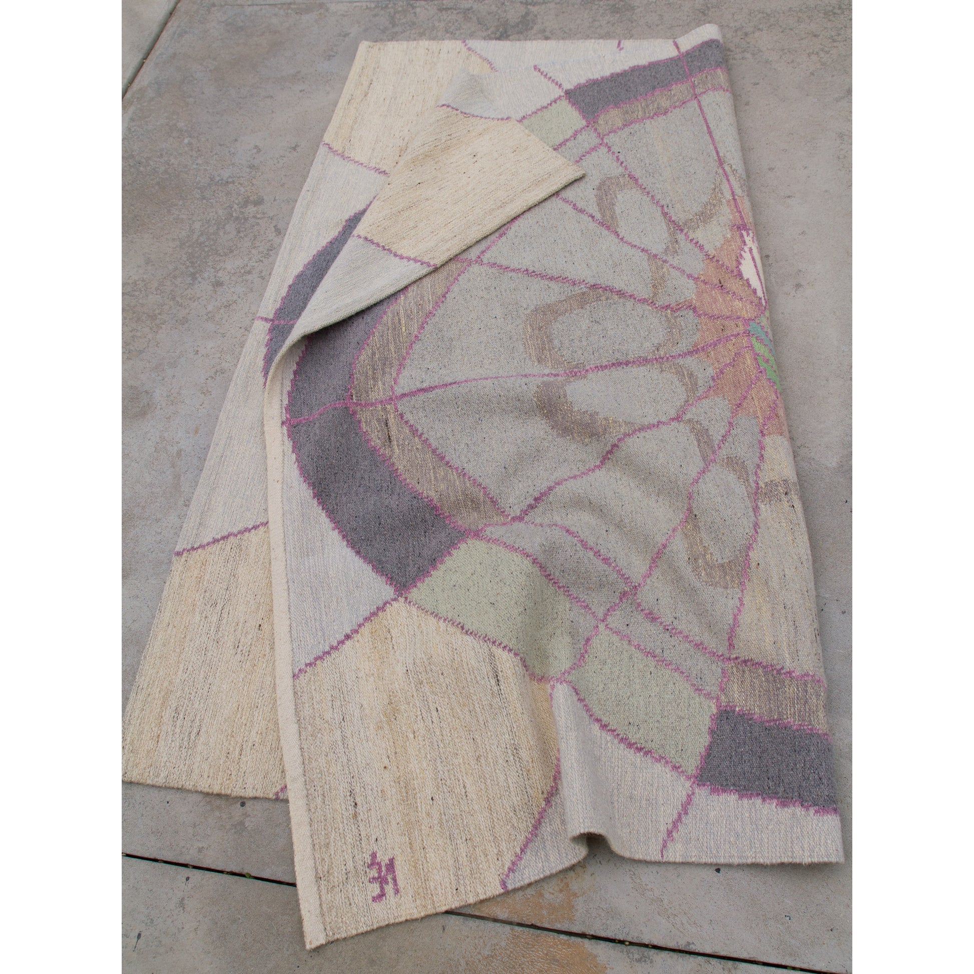 The huge vintage rug gathered on the ground to show its exceptional drape. It is strong enough for the floor but pliable enough to hang safely on a wall.