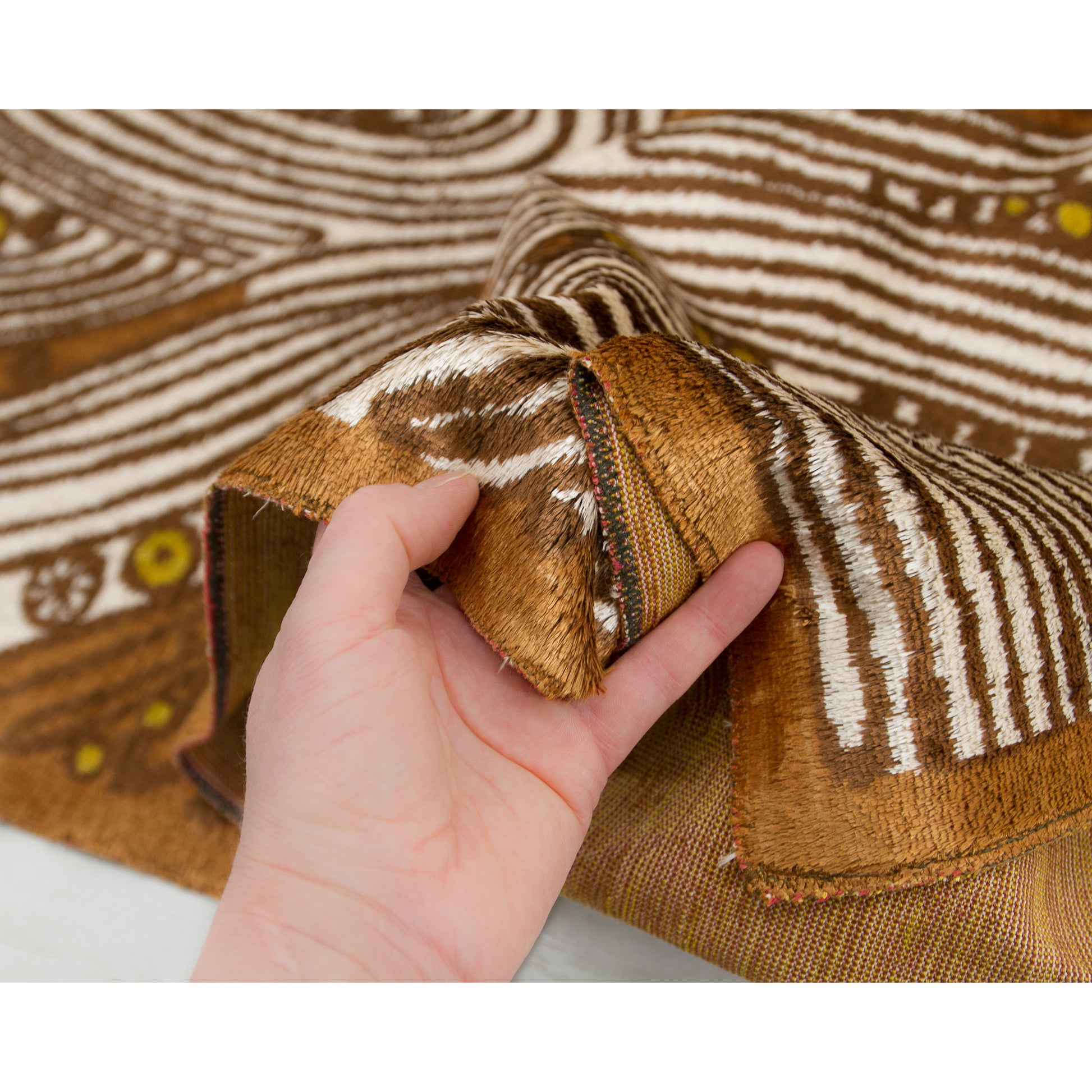 A draped corner gripped softly in a hand. Shows the stunning contrast between the shimmering, soft upper pile surface and the heavy-duty canvas weaving structure beneath it.