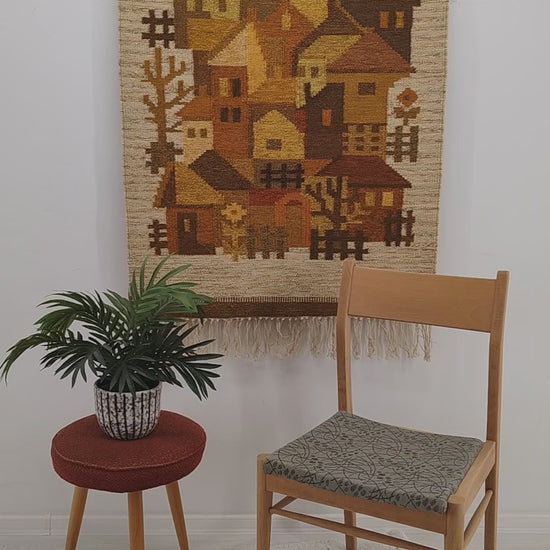 A detailed, sweeping video panning over a yellow and brown 1970s vintage tapestry, with a hand tightly squeezing the high-quality flatwoven fibers. Mellow, warm colors in a stylized, geometric design.