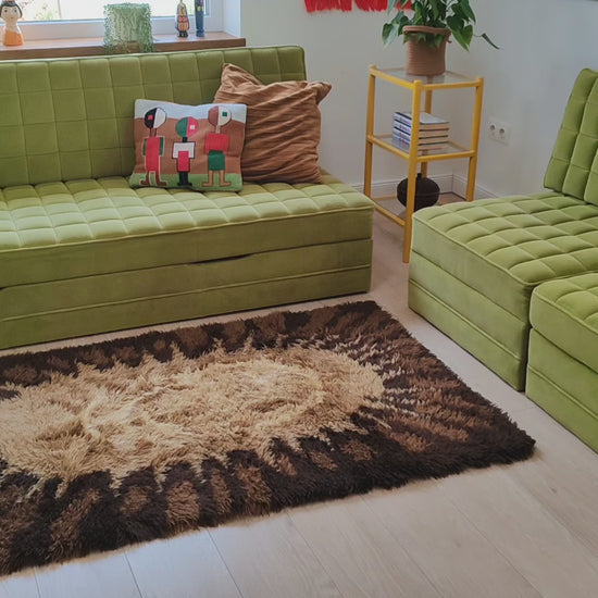Video of a vintage 70s rya style shag rug with sunburst design in brown, caramel and cream, showing how the thick, soft pile feels and moves when touched