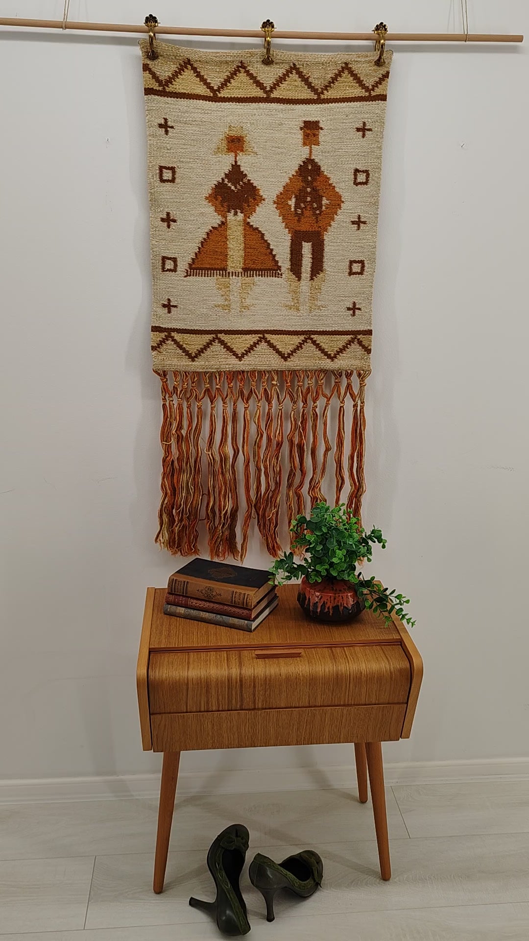 A brief video showcasing a vintage 70s orange and brown geometric tapestry. The textile is gently draped and folded in-hand to highlight the flexible, heavy handwoven quality and warm aesthetic earth tones.