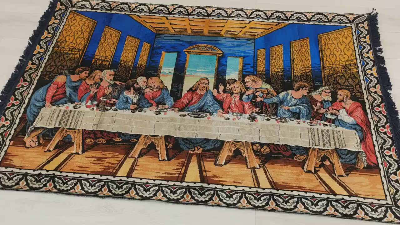 A detailed video sweeping over the majestic scale of a vibrant cobalt blue Last Supper tapestry. A hand touches and folds the fabric, demonstrating the soft, velvet-like moquette pile.