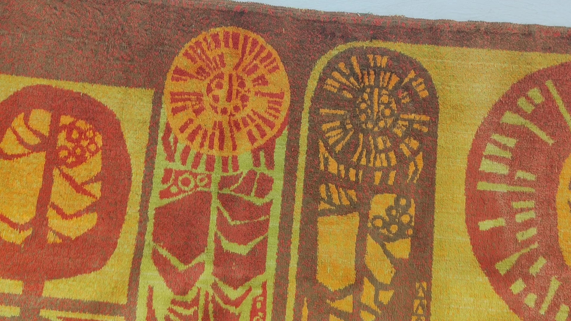 Video smoothly panning across the entirety of the earthy, glowing mid century tapestry and brushing across its thick, velvet-like fabric surface.