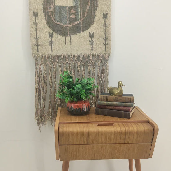 Slow panning video of the stunning pastel bird tapestry on a bright wall, followed by a hand rubbing the smooth flatwoven wool texture to showcase the tactile coziness of the material.