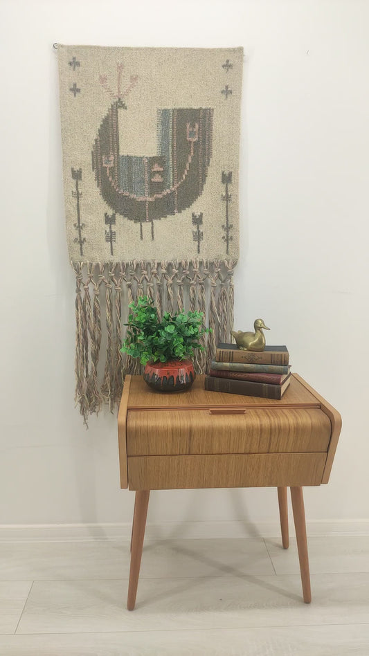 Slow panning video of the stunning pastel bird tapestry on a bright wall, followed by a hand rubbing the smooth flatwoven wool texture to showcase the tactile coziness of the material.