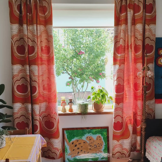 Pair of 1970s vintage curtains with bold Flower Power pattern hanging at a window in a retro style living room, also showing the texture of the high quality jacquard drape.