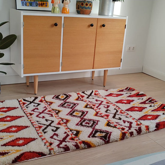 Detail video footage of the tribal patterned latch hook tapestry rug in a stylish bohemian living room. Perfectly proportioned, bright, and symmetrical rug for floor or wall decoration.