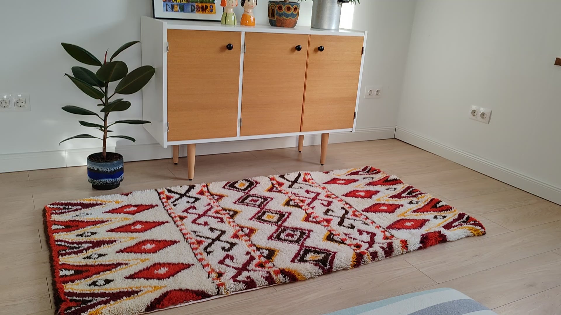 Detail video footage of the tribal patterned latch hook tapestry rug in a stylish bohemian living room. Perfectly proportioned, bright, and symmetrical rug for floor or wall decoration.