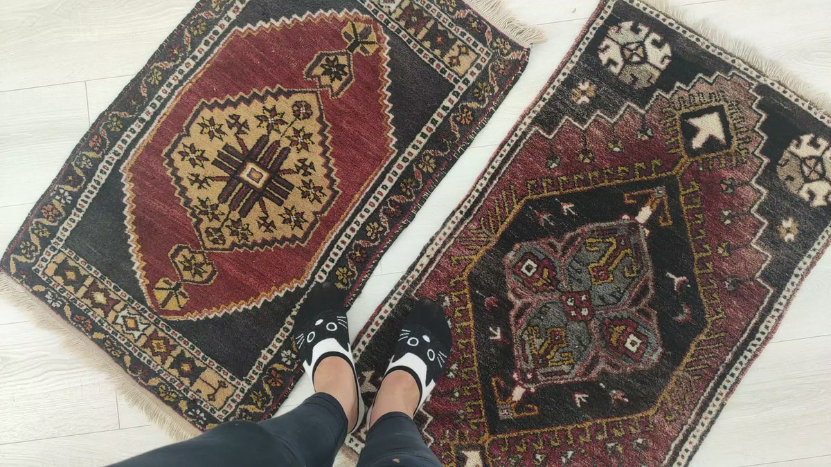 Close look at two small vintage Turkish yastik rugs, showing their colors, tribal patterns and hand-knotted wool pile.