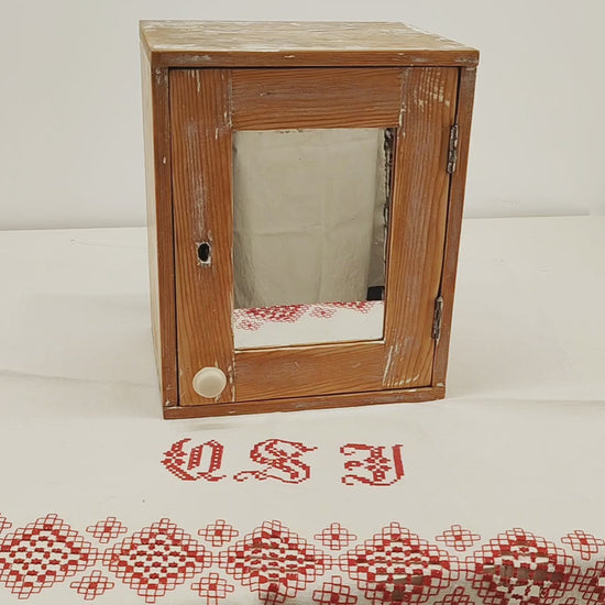 Video of a small vintage wooden wall cabinet or medicine cupboard with mirror door, showing the smooth satin wax finish, the original mirror, the door opening and the removable shelf inside