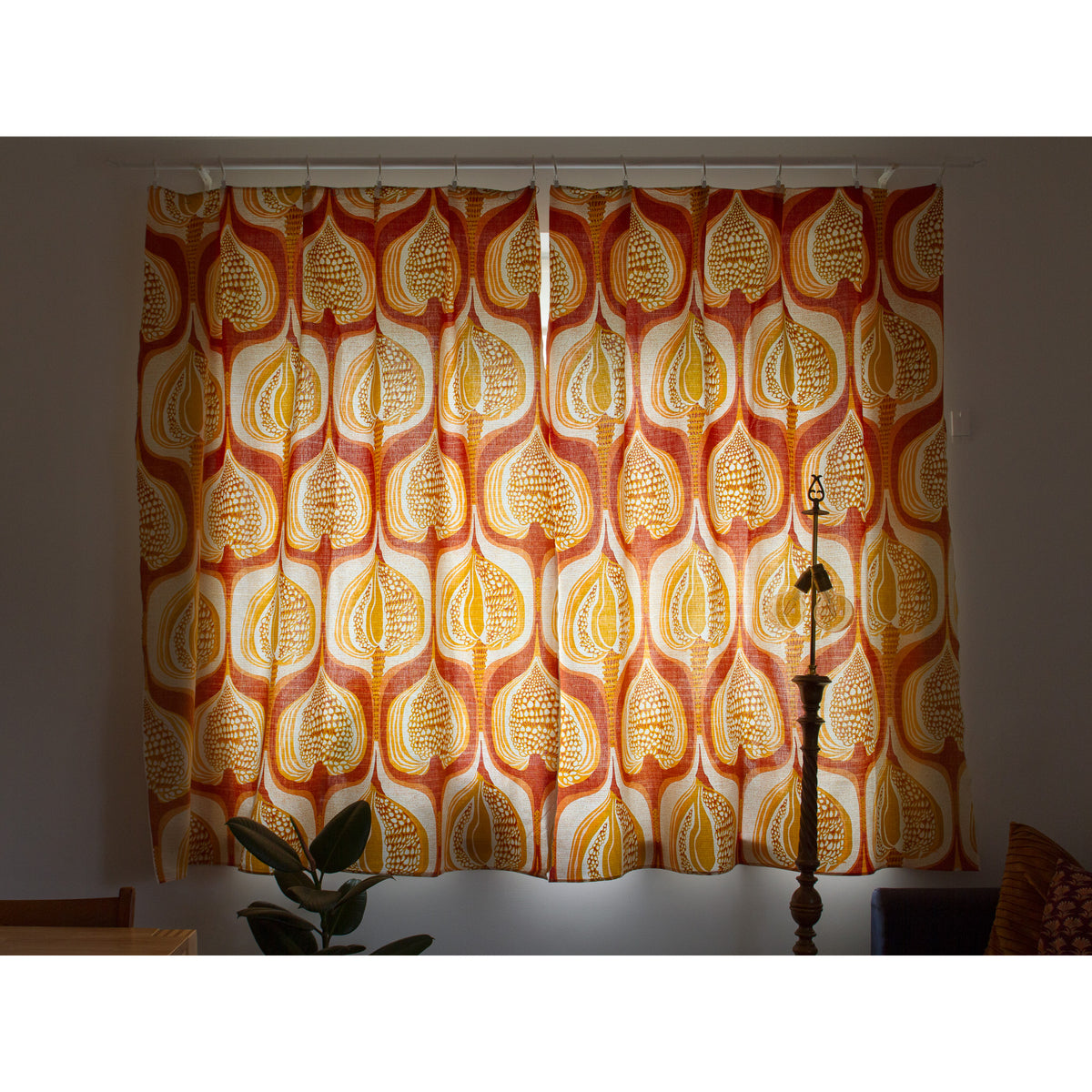 Retro mid century curtain panels glowing in warm sunlight, bold and organic seed pod pattern.