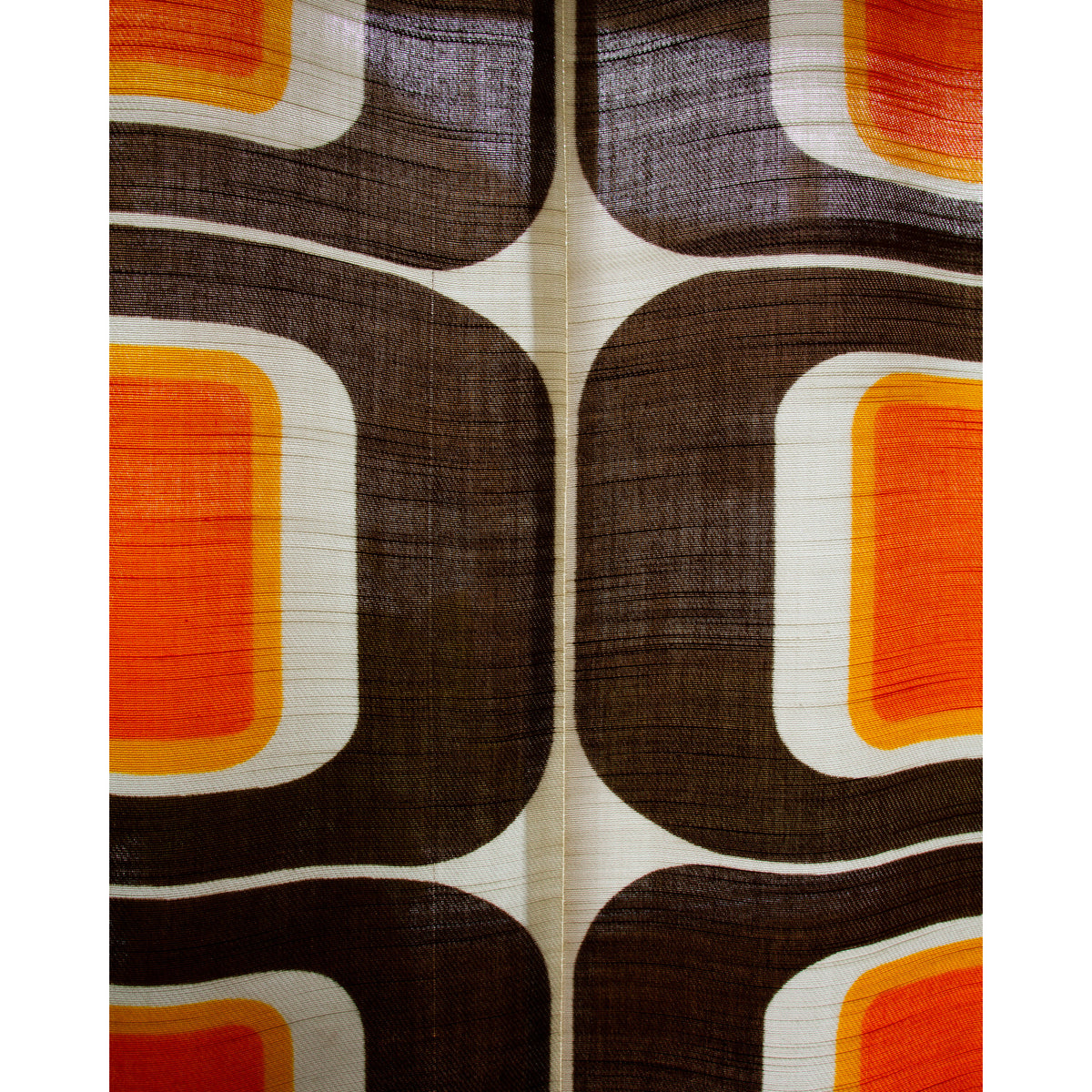 Extreme close-up of 1970s style pop art curtain fabric with rounded rectangle motif in orange, brown and cream