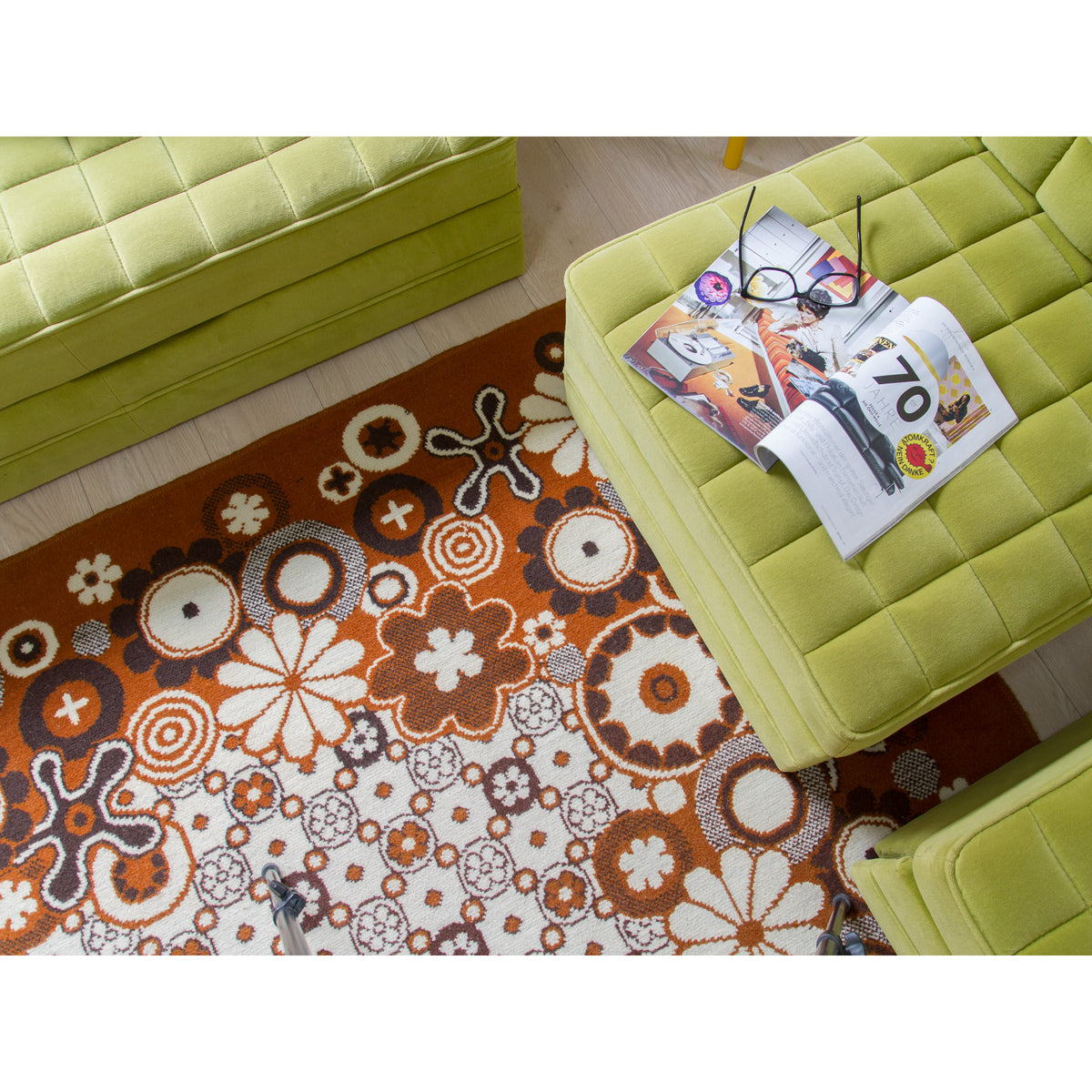 Retro 70s rug styled with a vintage magazine on a green pouf, cozy living room scene
