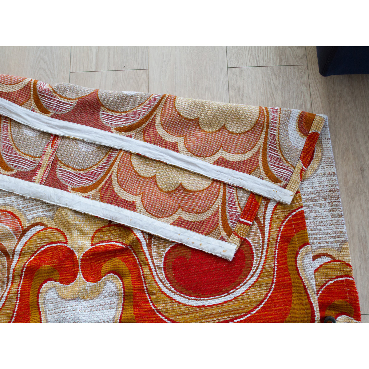 Back of an unlined vintage drape laid flat, showing the pleat tape sewn on the top