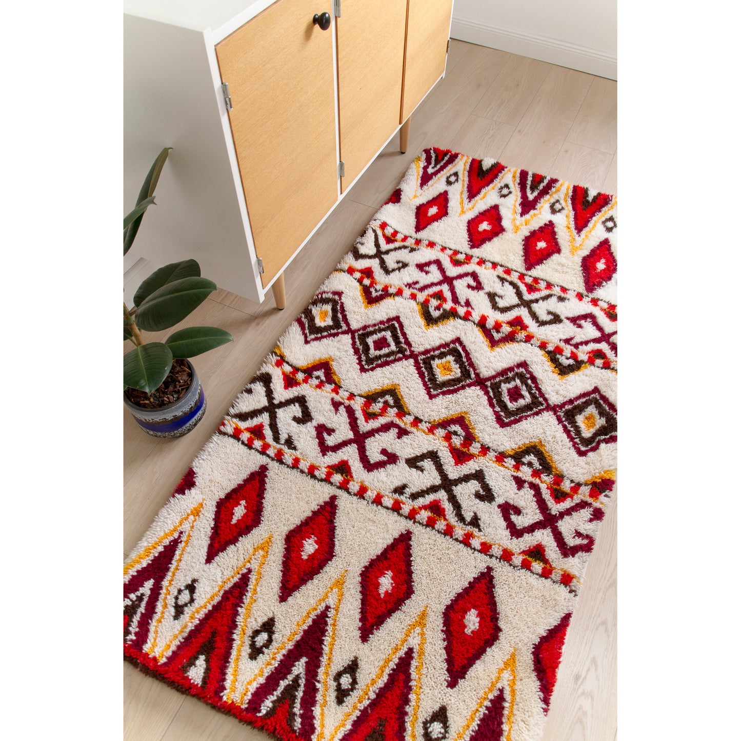 The 72x35 inch boho chic floor rug styled seamlessly in a bright modern room, perfectly scaled as a wide runner against a vintage teak credenza.
