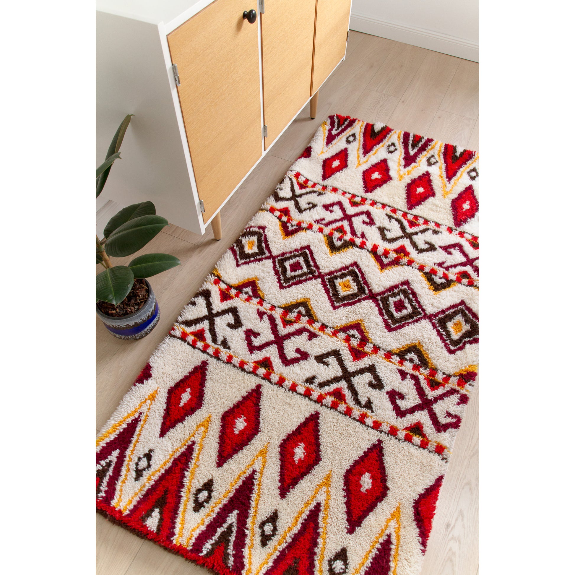 The 72x35 inch boho chic floor rug styled seamlessly in a bright modern room, perfectly scaled as a wide runner against a vintage teak credenza.