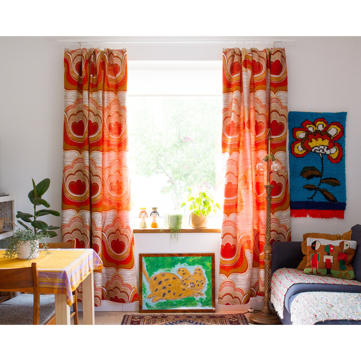 Retro orange and red vintage drapes framing a window in an eclectic boho living room with antique turkish rug and Flower Power wall tapestry