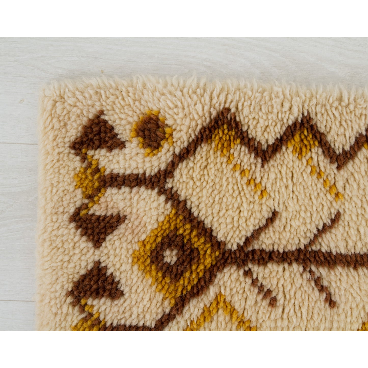 Macro focus near the horizontal side of the long tapestry rug showing the fluffy wool loops folding safely and beautifully over the durable inner binding base.