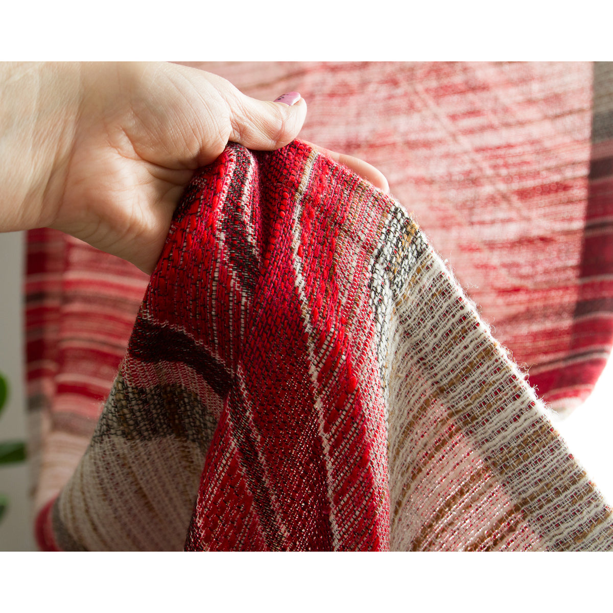 Hand lifting retro red woven fabric to show its weight, drape and chunky weave