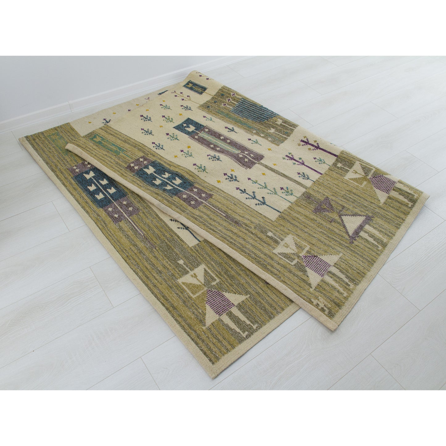 Giant mid-century floor rug folded halfway back onto itself over a floor, proving the clean, highly preserved condition of the reversible back side.