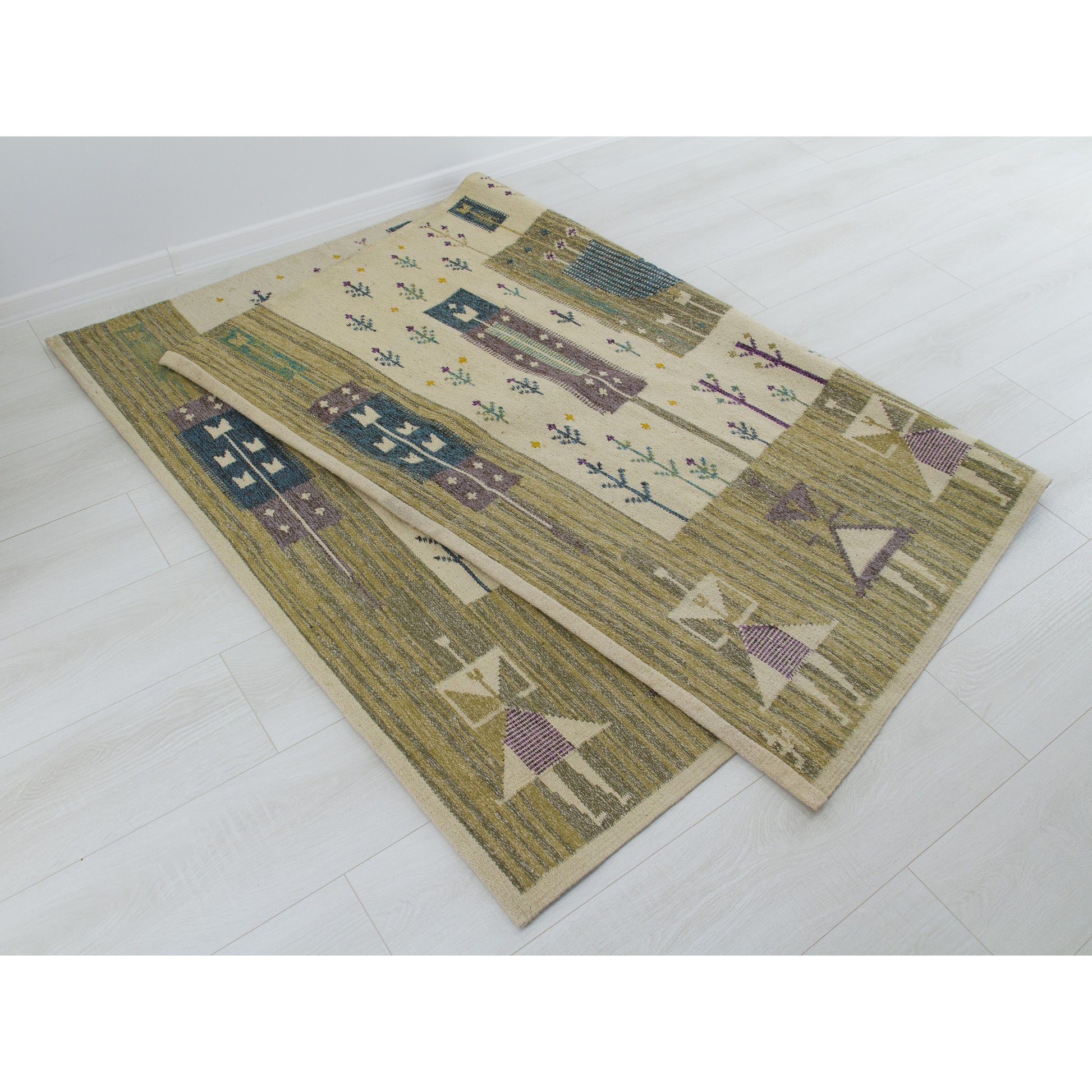 Giant mid-century floor rug folded halfway back onto itself over a floor, proving the clean, highly preserved condition of the reversible back side.