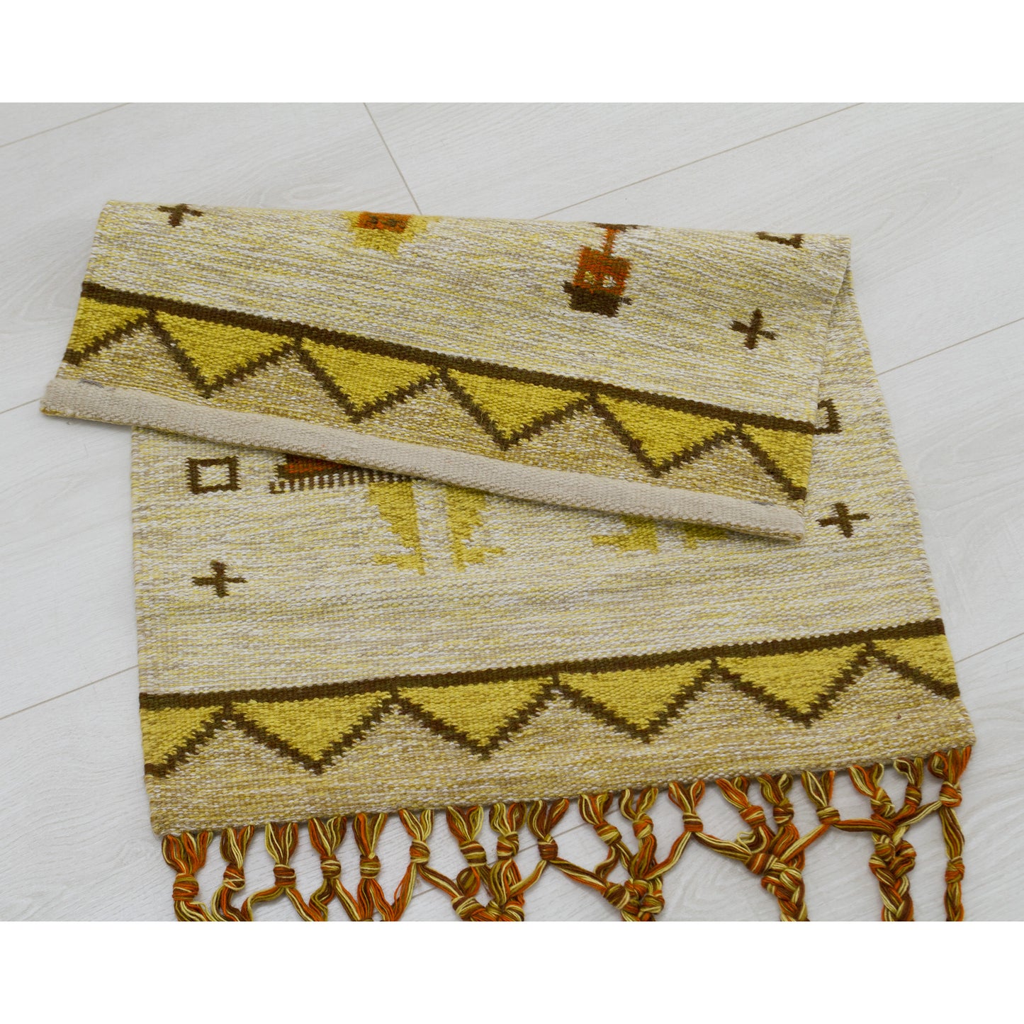 The top edge of the vintage mid century textile laid flat and folded over onto itself, perfectly demonstrating the immaculate, reversible backside, the expertly hemmed top border, and clearly showing that no mounting hardware is attached.