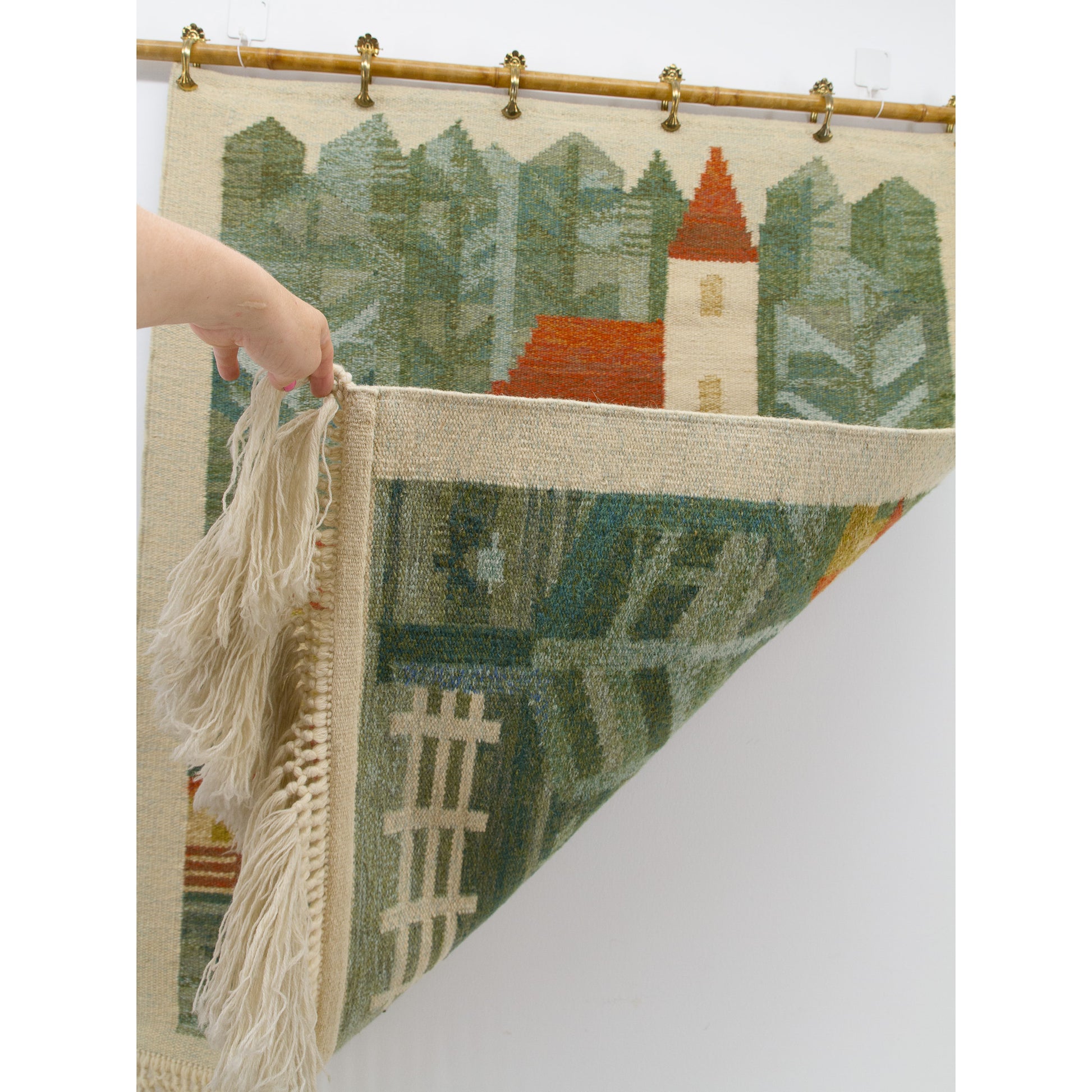 One corner of the artwork is peeled upwards by hand, revealing that the complex, vivid geometric village colors mirror perfectly on the fully reversible back.