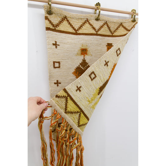 Hand lifting one bottom corner of the hanging vintage textile to reveal the perfectly identical, beautifully preserved and reversible back side.