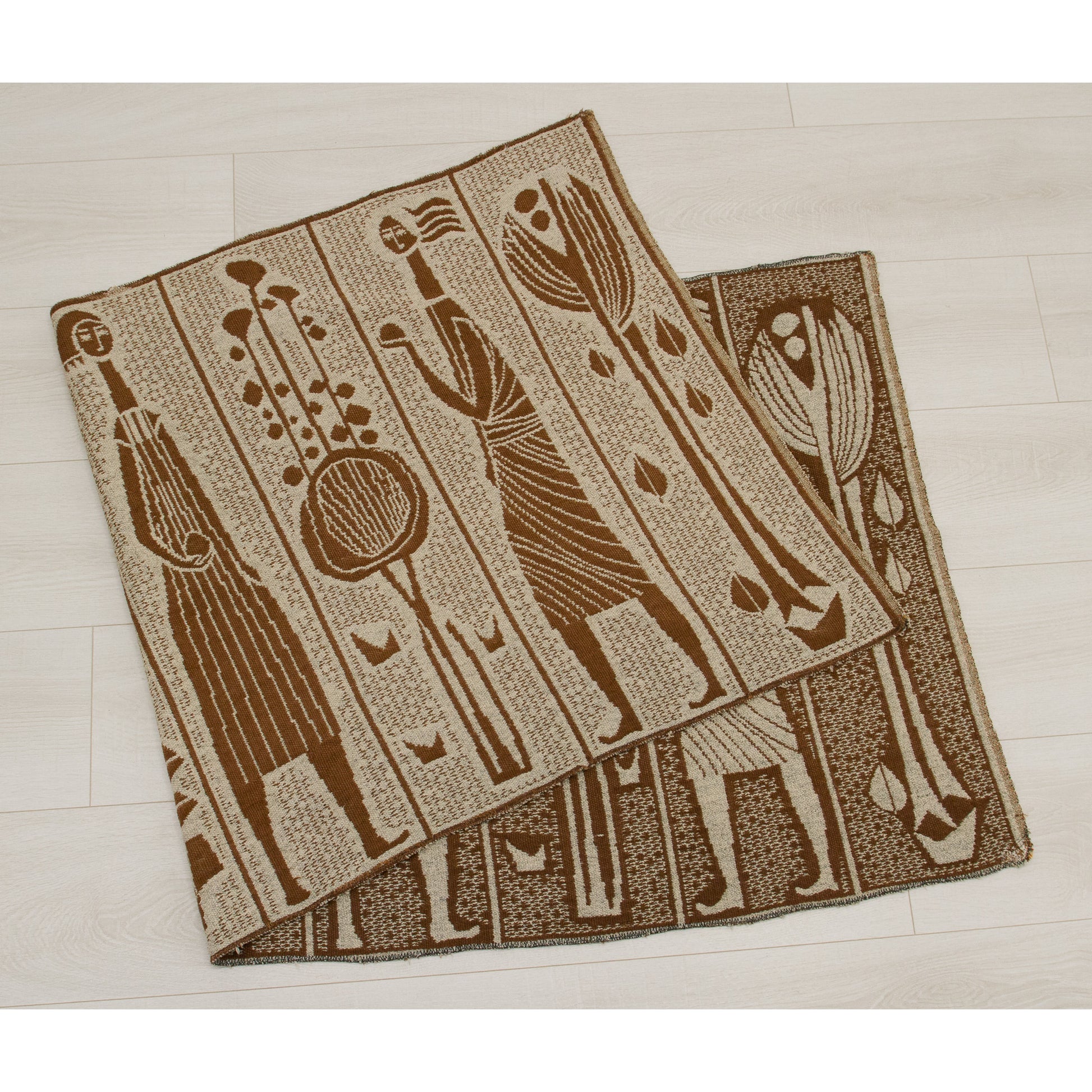 Folded vintage woven textile showing the reversible pattern. The underside features a darker charcoal geometric design, suitable for use as a table runner or wall hanging.