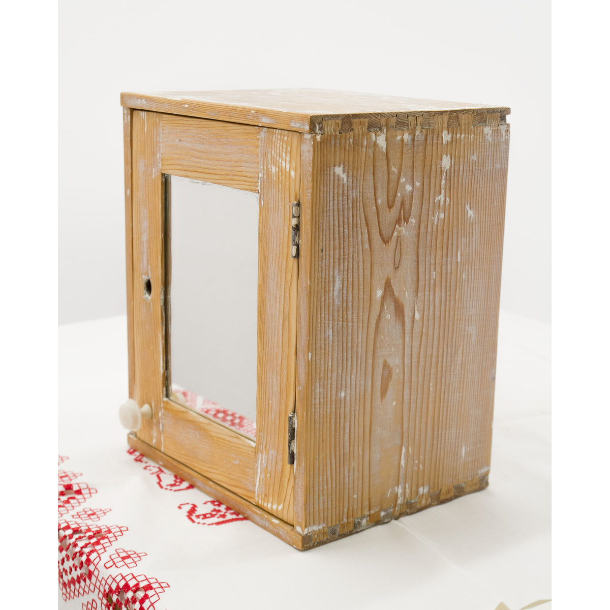 Carefully refurbished rustic wooden wall cupboard or medicine cabinet, featuring an antique mirror door and a small white knob, with a strong farmhouse or cottagecore style.