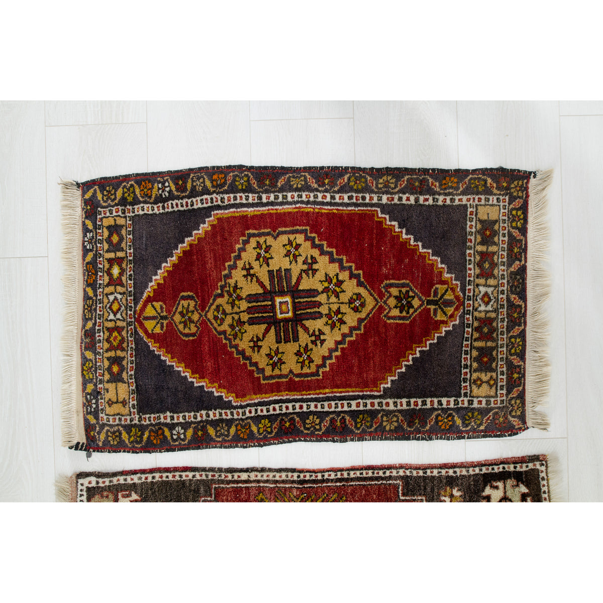 Small vintage red Turkish rug with a golden stepped medallion, navy corners and ivory fringe