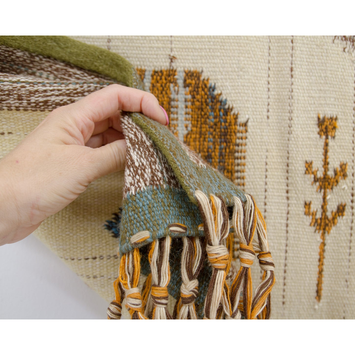 Hand comfortably grasping the draped, heavy mid-century textile, demonstrating its pliable yet strong weave quality and the beautifully neat, hemmed side edge.