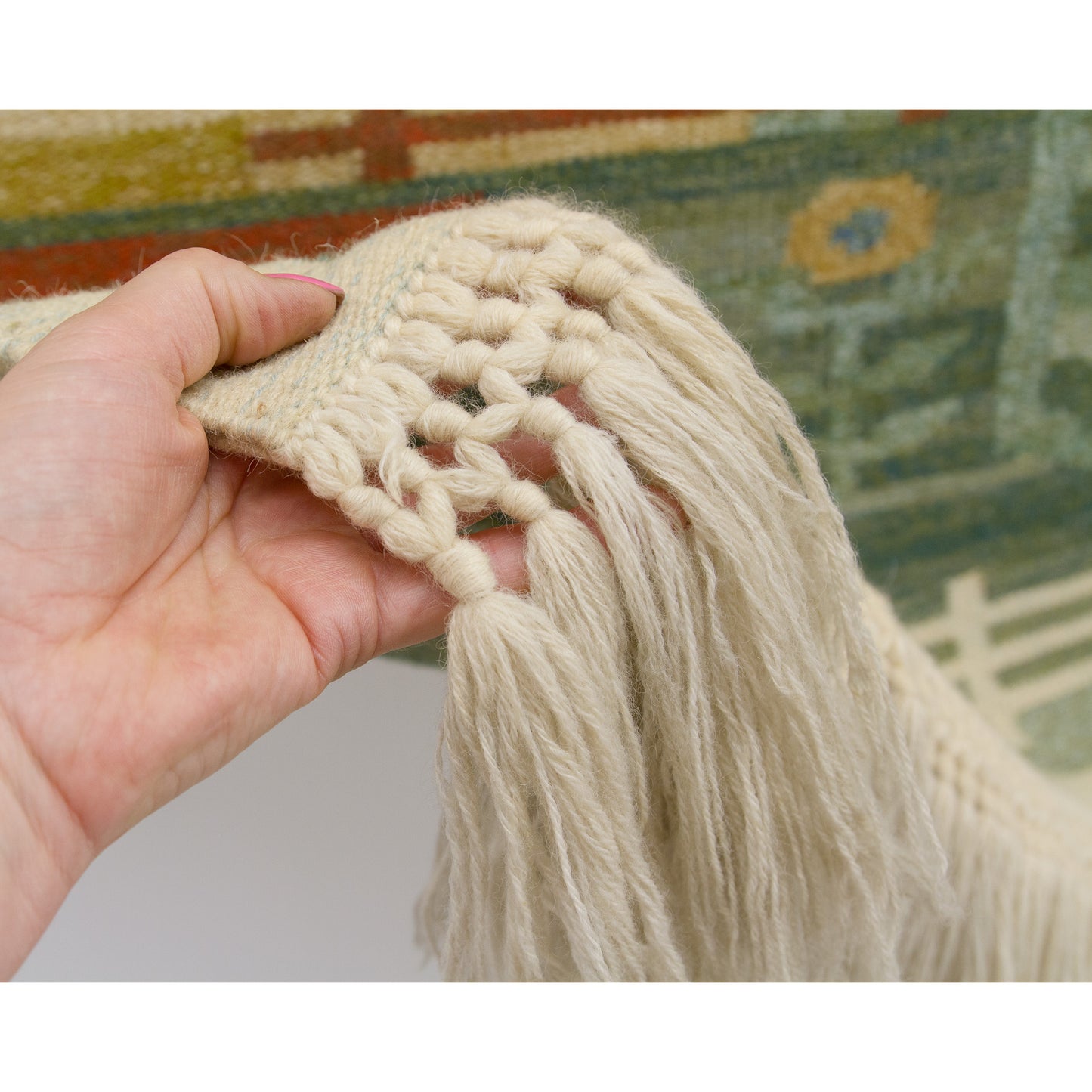 Hand comfortably lifting the incredibly soft wool and cotton blended fringe strings to help viewers sense the beautiful tactile quality.