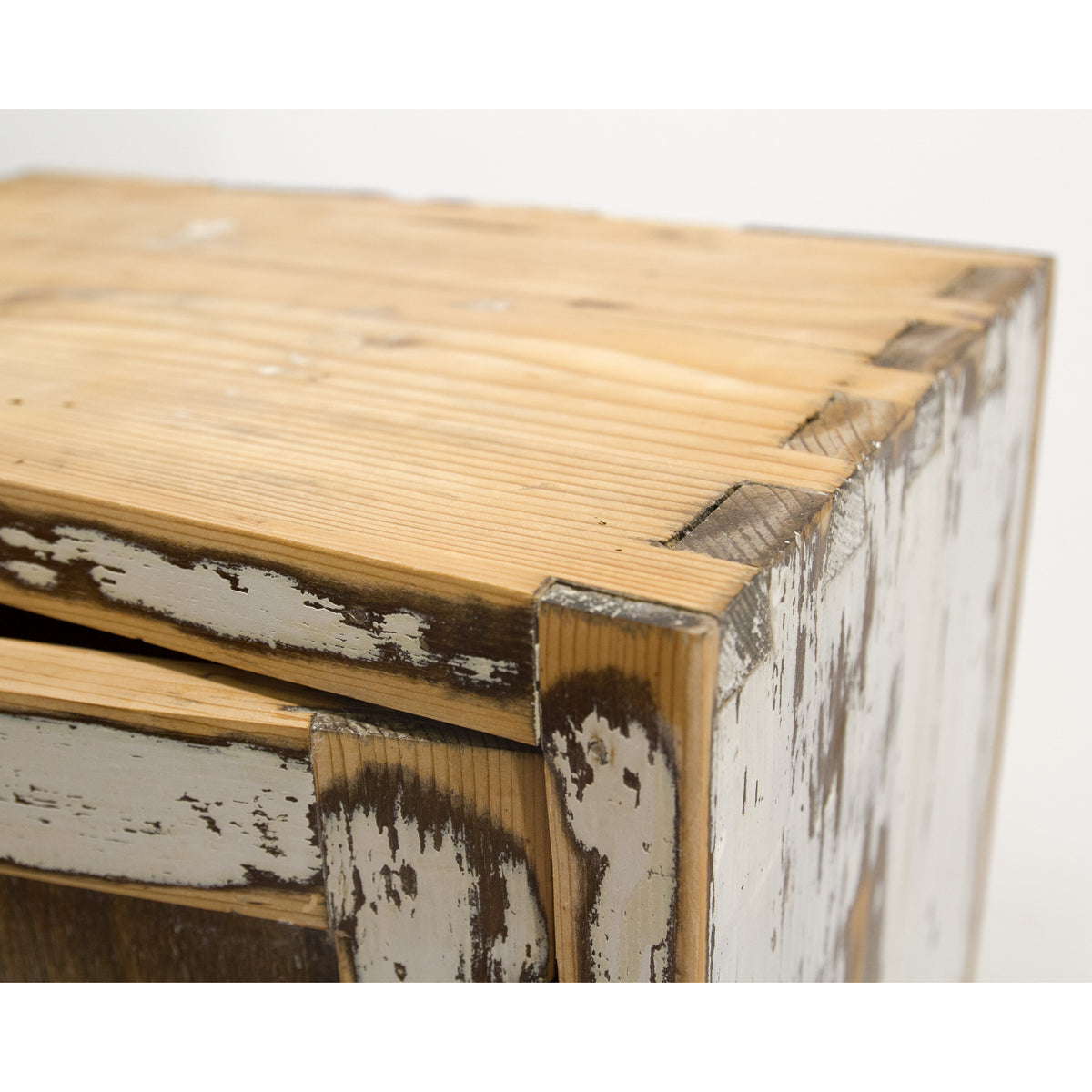 Close-up of a refurbished rustic wall cabinet with distressed white paint showing through the chipped finish, highlighting natural wood grain and dark brown wood accents.
