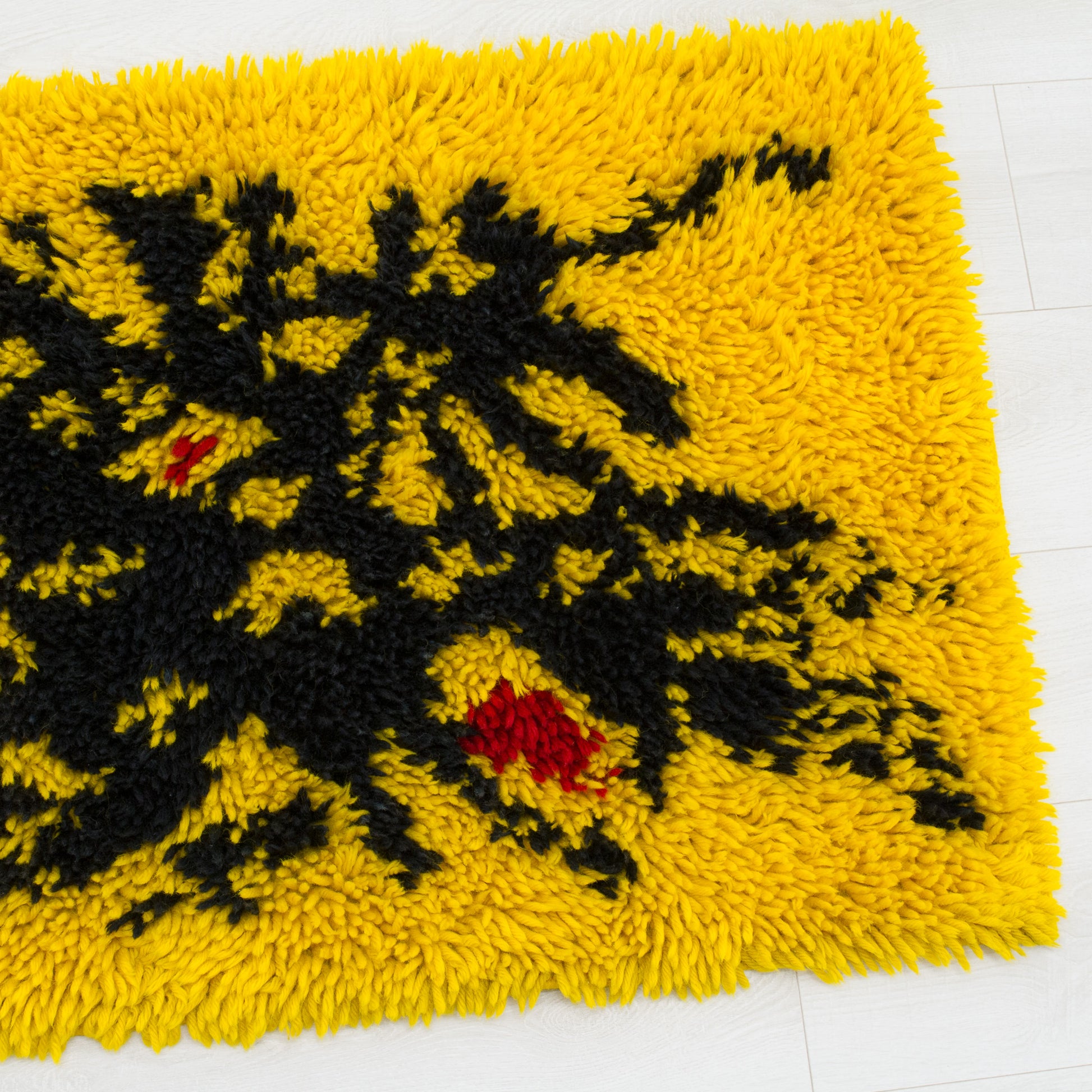 Close-up of the extra high piles of the multi-purpose rug. The high pile shag texture contrasts vivid yellow and pitch black in this vintage mid century wall tapestry.