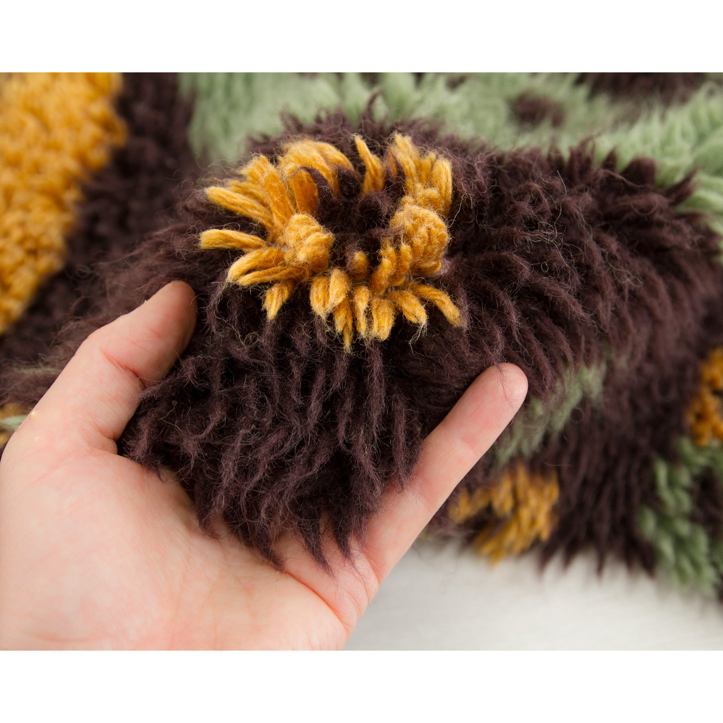 Hand gracefully brushing up against the dark brown side border of the vintage textile, capturing the very pleasant, fuzzy sensation of the heavy-pile textile.