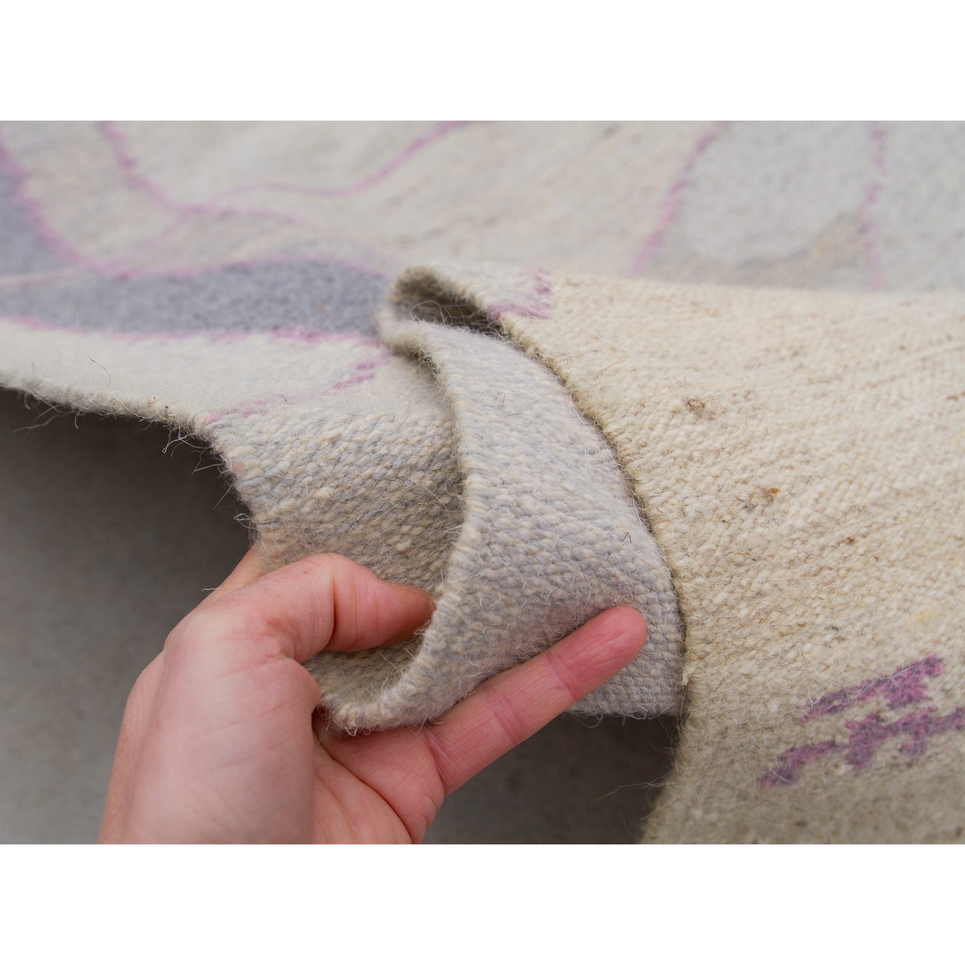 Hand gripping the edge to showcase the incredible textural density and weight of the high-quality woven wool-weft and cotton-warp construction.