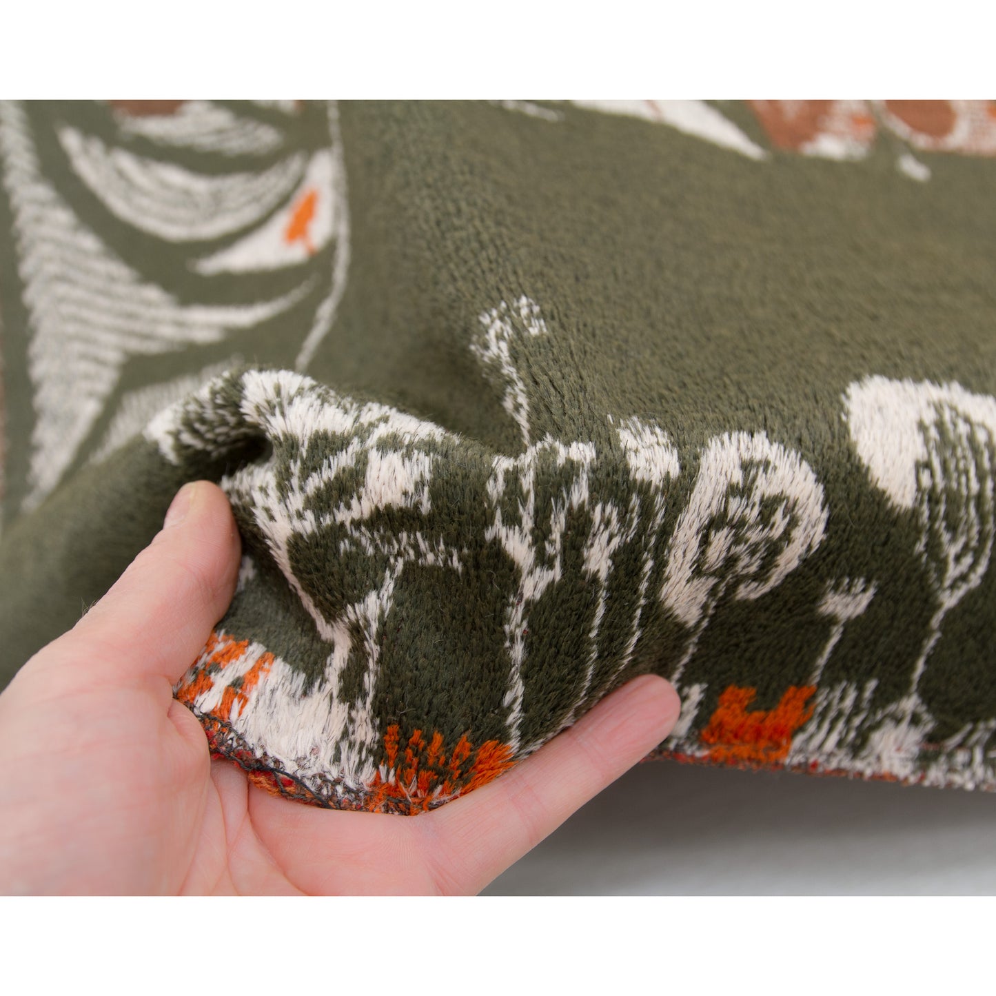 A hand gripping the sturdy edge of the wall tapestry. Highlights the unique, non-shiny velvet-like pile that adds immense tactile warmth and texture to stark mid century interiors.